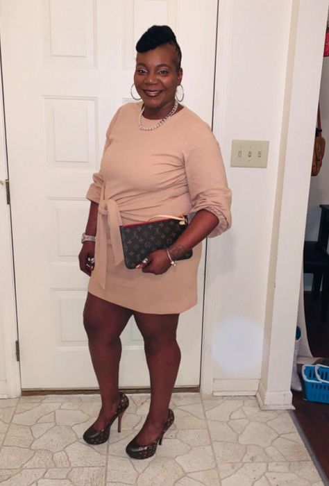 A reviewer modeling the light pink dress paired with black heels