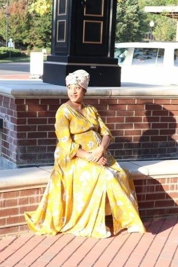 A pregnant reviewer modeling the yellow maxi dress
