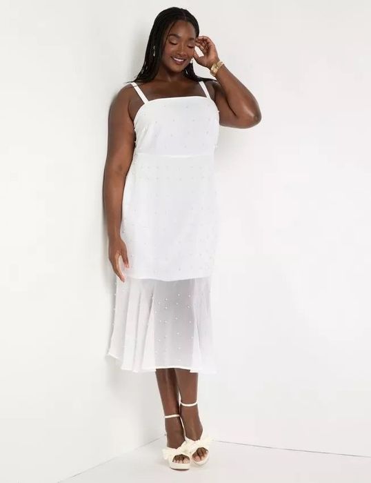 A model wearing a white dress and white heels.