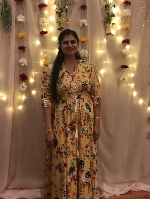 A reviewer wearing the yellow floral maxi dress featuring button and tassel details with 3/4 sleeves