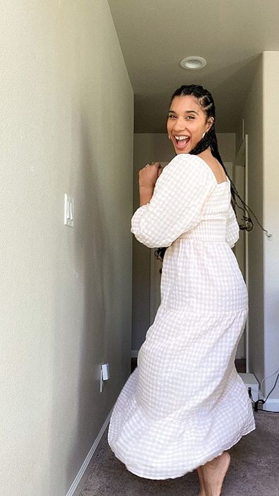 A reviewer showcasing a tan and white dress.