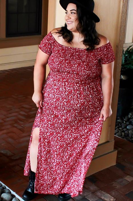 A reviewer showcasing the red dress adorned with a white floral pattern.