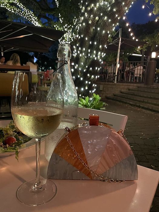 a reviewer’s clutch placed on a table beside a glass of white wine