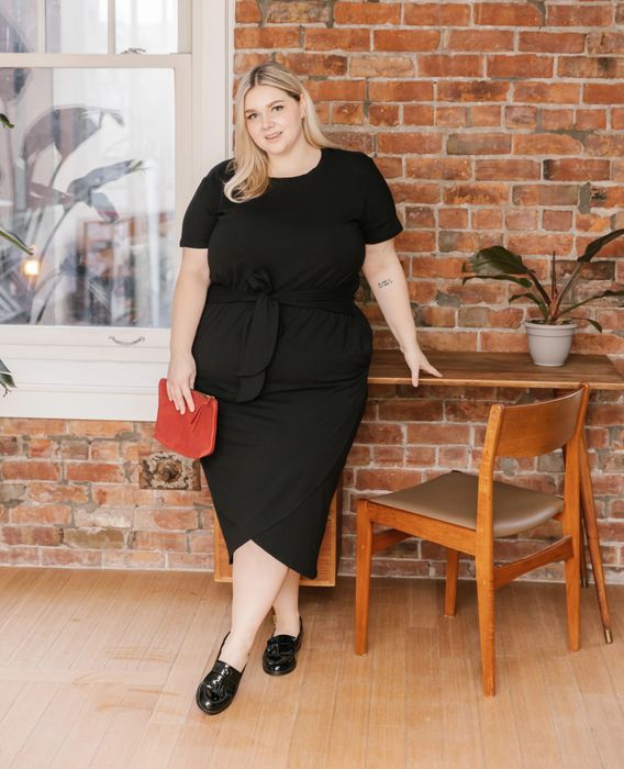 A model wearing a black dress paired with black shoes.