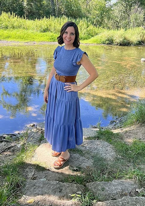 A reviewer showcasing the blue dress styled with leather sandals