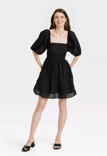 A model posing in an elegant black lace dress.