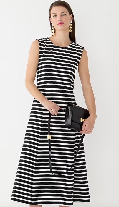 A model wearing a black and white striped dress, paired with a black bag.