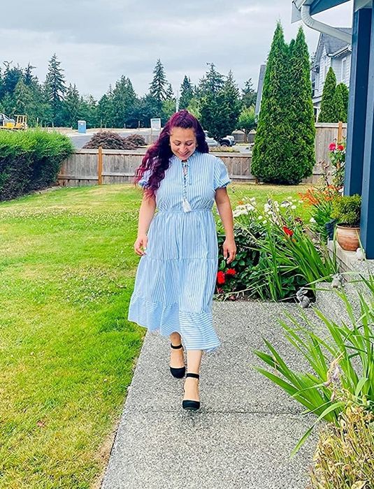 A reviewer in a blue and white dress, paired with black shoes.