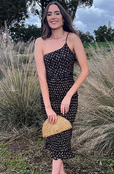 A model styling the black floral dress, paired with a tan bag