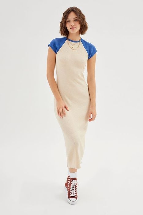 A model rocking a white and blue dress, completed with red shoes, white socks, and a blue-and-white baseball cap.