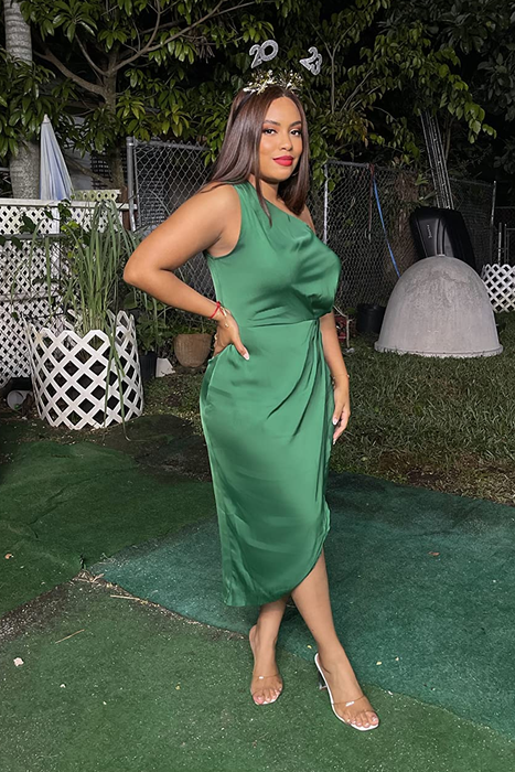 A reviewer striking a pose in the green dress, showing off its elegance