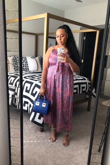 A reviewer wearing the same tie-front satin dress, but in a blue and pink leaf print design.