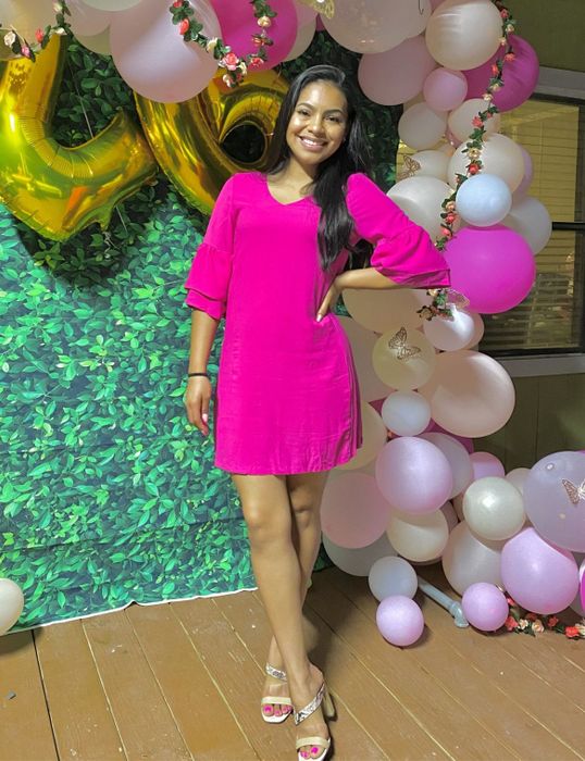A reviewer showcasing the pink dress paired with slide heels