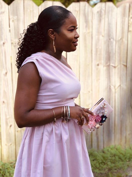 a reviewer holding the pink floral clutch