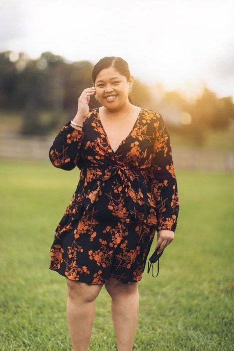 A reviewer in a black and orange floral dress