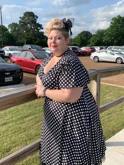 A reviewer models the dress in black, adorned with classic white polka dots for a timeless look.