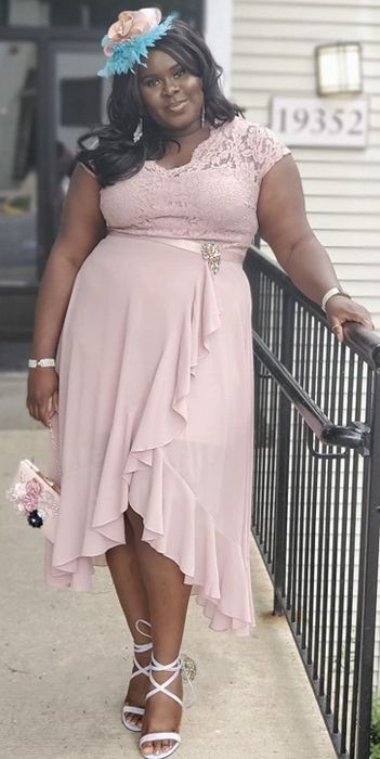A reviewer wearing the dress paired with a playful hat and strappy sandals