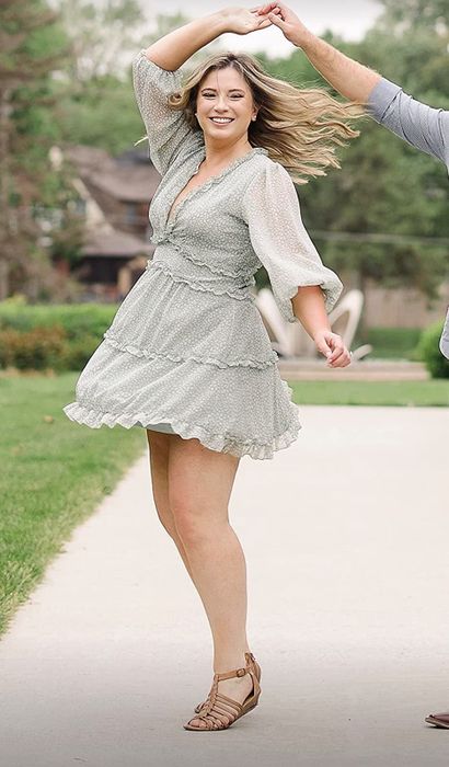 A reviewer modeling the light green dress with brown sandals