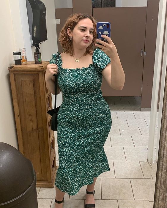 A reviewer wearing the same dress in a green and white floral print