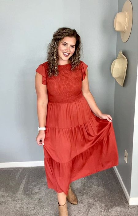 A reviewer modeling the red dress paired with boots