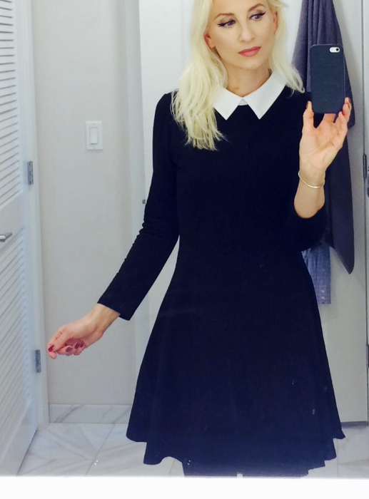 A reviewer wearing the black long-sleeved dress with a white collar