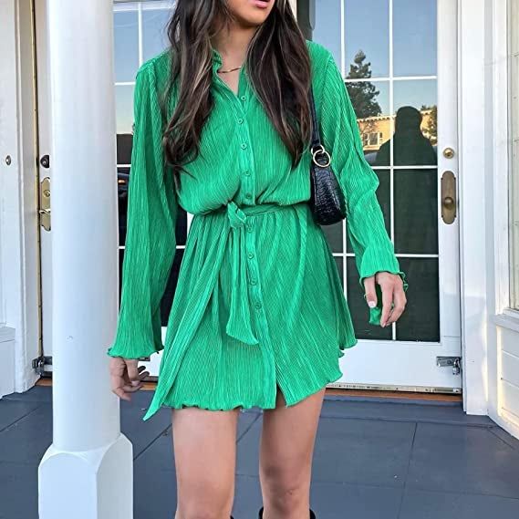 A model showcases the elegance of a green dress, striking a poised pose.