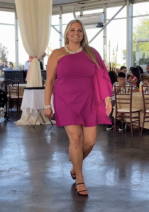 a reviewer showcasing the fuchsia one-sleeve shift dress