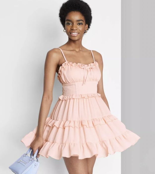 A model showcasing the dress in a soft pink hue