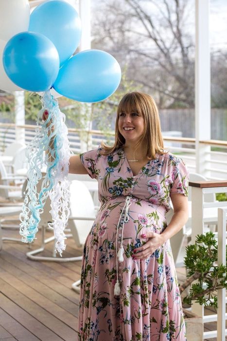 reviewer wearing the pink dress while holding a bunch of blue balloons