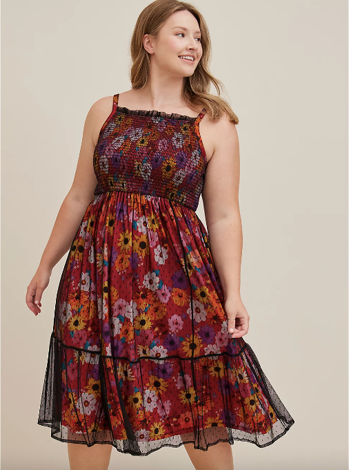 Model wearing a square-neck, sleeveless red floral dress with a black sheer overlay