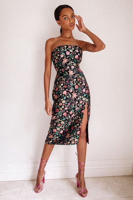 Model in a below-the-knee dress featuring colorful floral patterns and a daring high side slit
