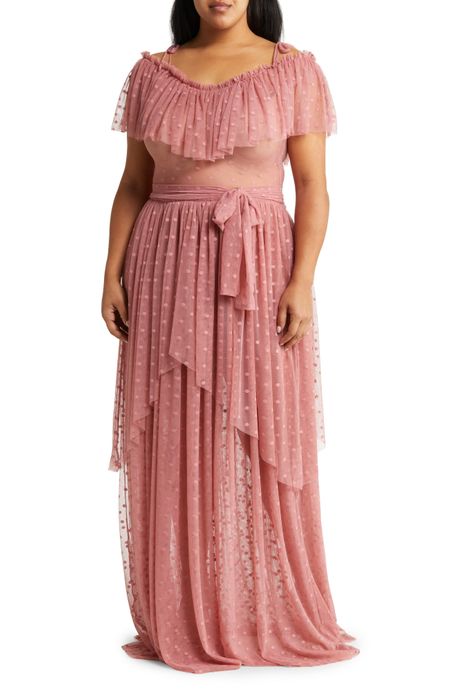 A model poses in a pink layered tulle gown featuring an off-the-shoulder neckline and delicate tie straps at the shoulders.