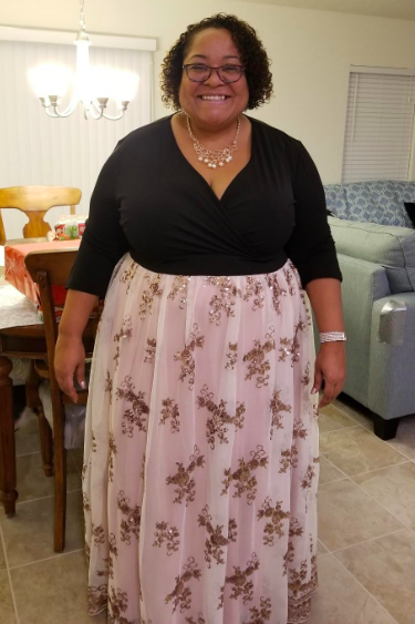 A reviewer is pictured in a three-quarter sleeve gown with a black bodice and a white embellished skirt.