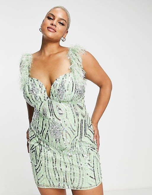 Model wearing a mint green, body-hugging mini with plunging neckline, feather-trimmed straps, and shimmering silver sequins and jewels