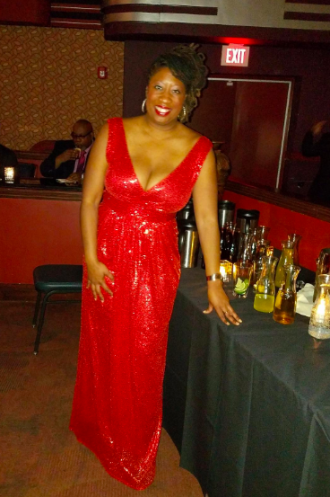 A reviewer showcasing the plunging neckline, sleeveless, full-length red gown
