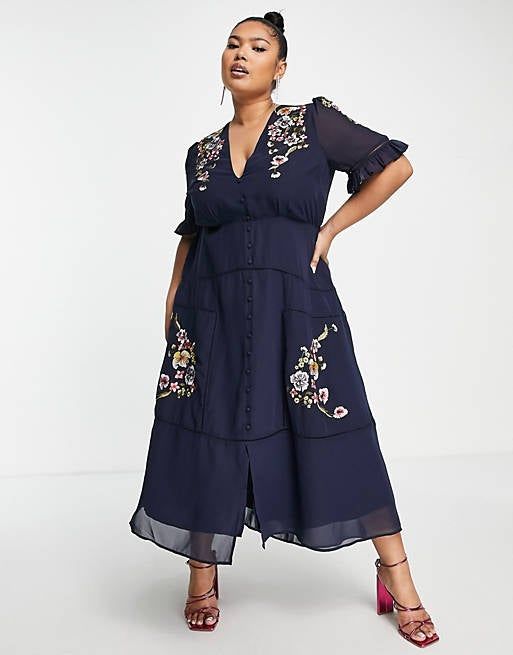 Model showcasing a dress with elbow-length sleeves, a flattering v-neck, and vibrant floral embroidery.