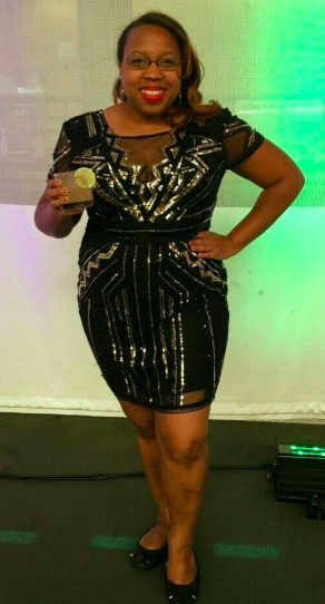 Reviewer wearing a black, short-sleeve, above-the-knee dress featuring art deco sequins and sheer panels