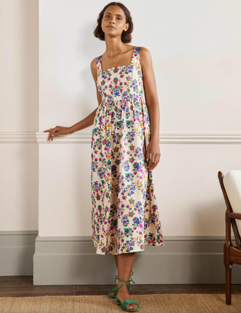 A model wearing an off-white midi dress adorned with a colorful print.