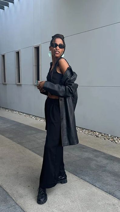 Reviewer in a leather jacket and sunglasses, rocking wide-leg pants and boots while walking in an urban setting
