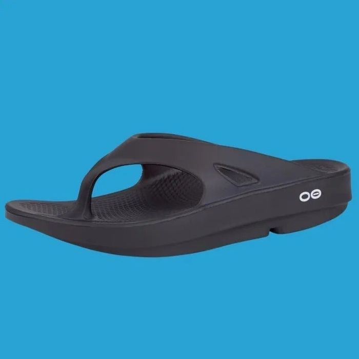 A sleek, black ergonomic flip-flop sandal with a thick sole and textured footbed, set against a simple background.