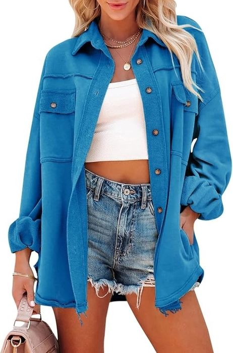 Person in a casual outfit wearing a blue oversized shirt, white crop top, and denim shorts, holding a beige handbag