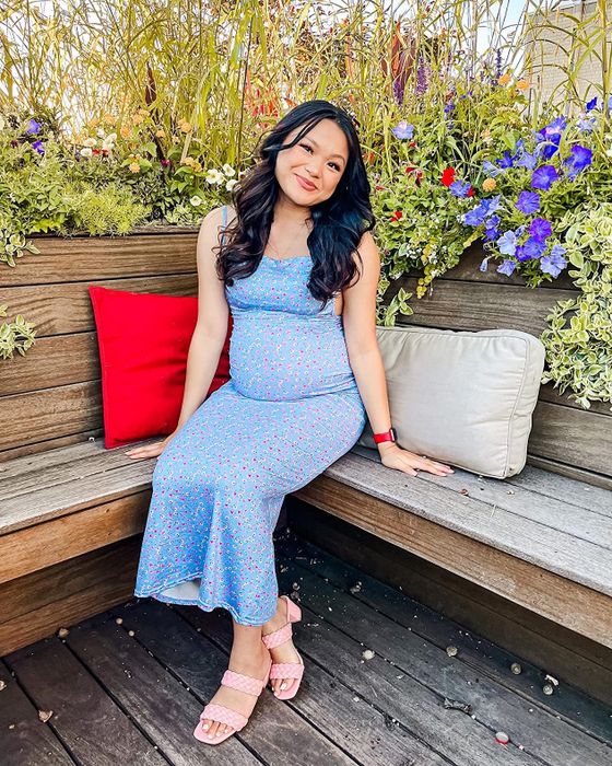 A reviewer seated on a wooden bench, showcasing pink sandals