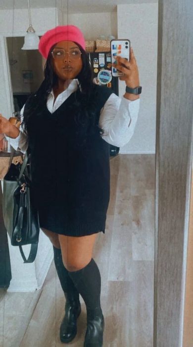 Reviewer wearing the black sweater vest over a white collared shirt, accessorized with a red beret, black shoes, and knee-high socks