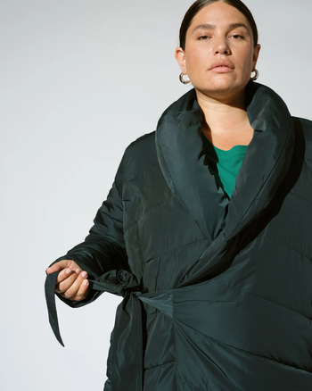 Person wearing the green version of the coat, showcasing the wrap belt closure