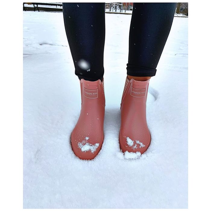 A reviewer standing in the snow, wearing stylish pink ankle boots