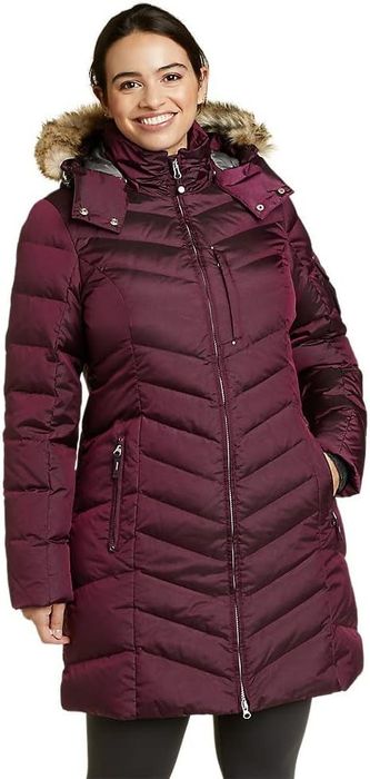 A person is seen wearing a purple knee-length puffer coat with a fur-lined hood, ideal for keeping cozy during winter.