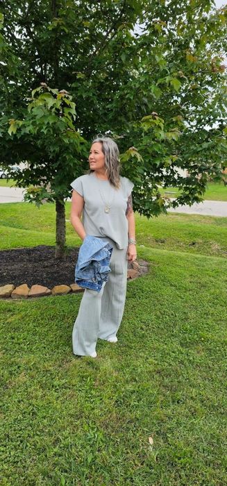 a reviewer outdoors holding a denim jacket, wearing a stylish blue set