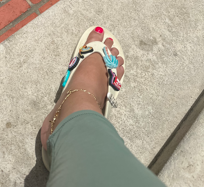 The author modeling white Crocs sandals featuring a butterfly design