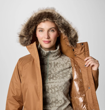 Person wearing the same coat in brown, highlighting the faux fur-lined hood and cozy interior lining