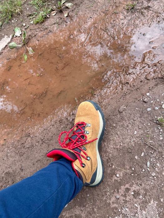 A reviewer modeling tan hiking boots accented with red laces